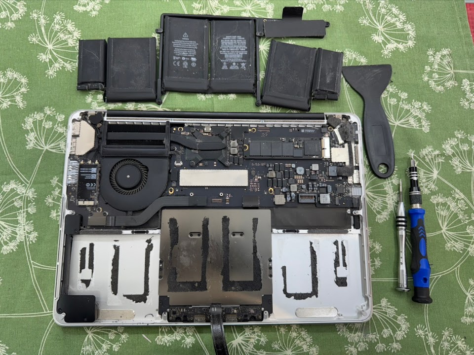 A MacBook opened on the bench during a battery replacement at the PMM Solutions Morden workshop, typical of Sutton home and office laptops